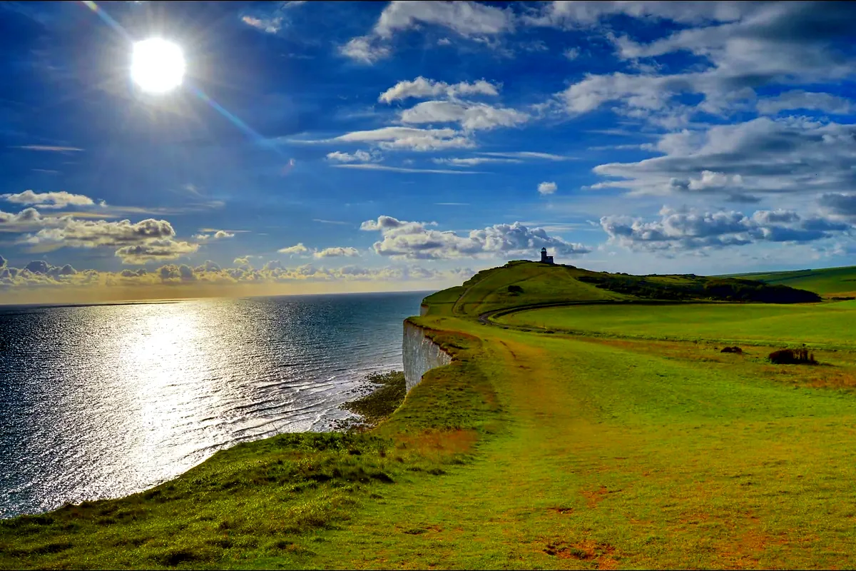 Le bianche scogliere del Sussex con il faro di Belle Tout e il mare al tramonto